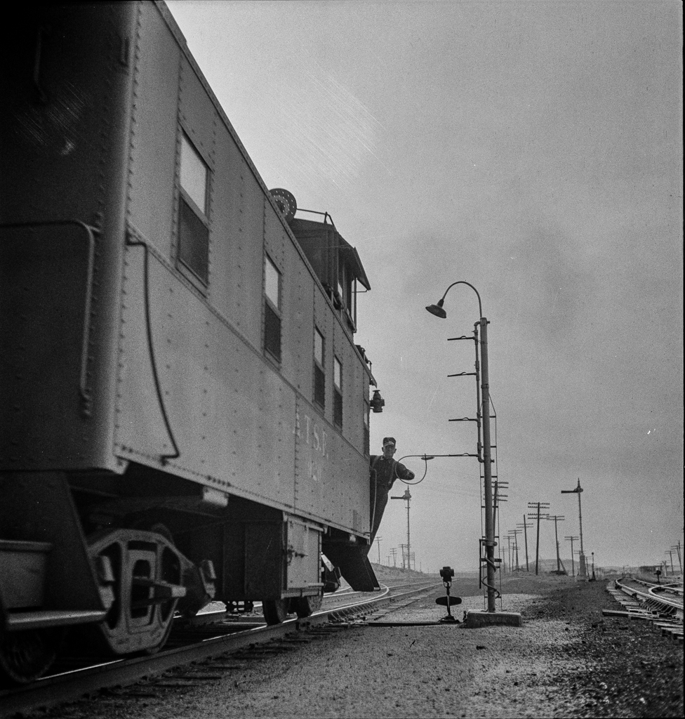 Isleta, New Mexico. Conductor of a passing freight train on the Atchison, Topeka and Santa Fe Railroad picking up a message
